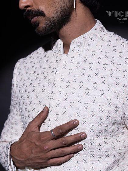 A close-up of the intricate geometric embroidery on one of our white sherwanis. This image highlights the precision and texture that define our craftsmanship.