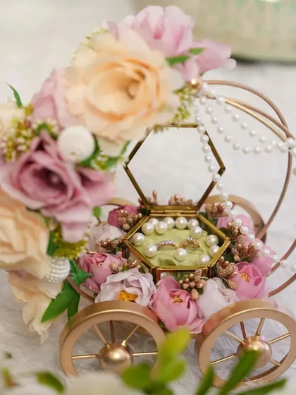 This isn't just a ring platter; it's a centerpiece. Our "Ring on Wheels" carriage, adorned with pastel florals and delicate pearls, makes the ring exchange ceremony truly magical and unforgettable.