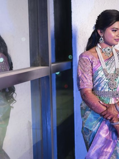 A portrait of the bride, showcasing her unique pastel saree and diamond jewelry. The makeup features a pop of color on the eyes to complement the outfit.