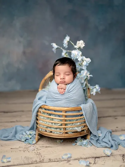 A little prince in dreamy blue. This classic newborn pose in a basket, surrounded by delicate blue flowers, creates a serene and handsome portrait.