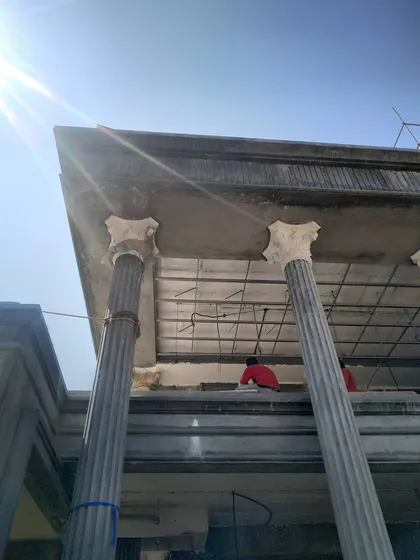 A close-up of the construction process, showing the installation of precast column capitals and the framework for the ceiling.