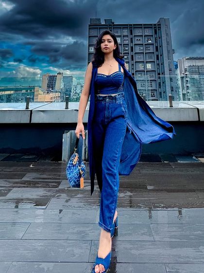 A walking shot of the all-blue denim look on the wet rooftop. The movement of the shrug adds a nice flow to the outfit.