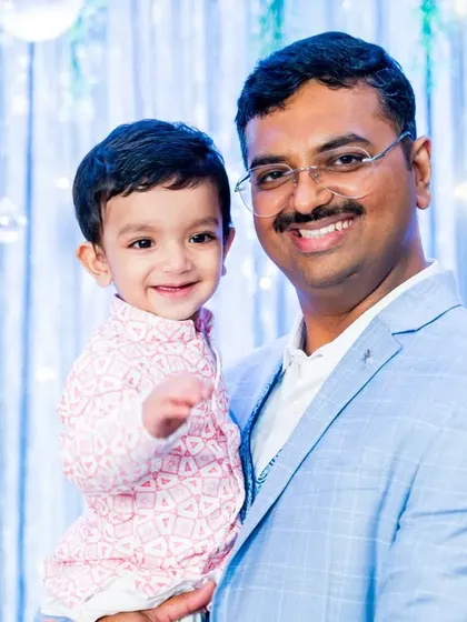 A proud father holds his smiling one-year-old son during his birthday celebration.