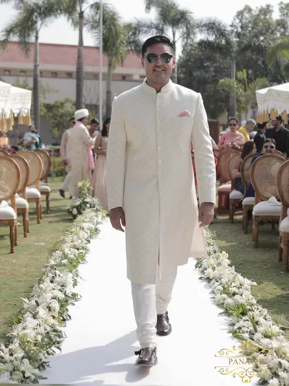 The groom makes his way down the floral-lined aisle, ready to meet his bride.