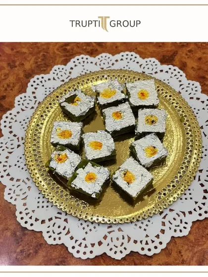A golden platter of our exquisite Kaju Katli, decorated with silver vark. A classic Indian sweet that is a symbol of celebration.