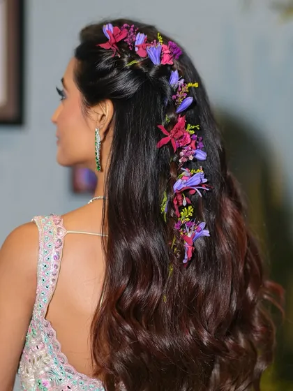 A detailed shot of the floral braid, a key element of this Mehendi look. The fresh flowers woven through her hair add a touch of natural, romantic beauty that complements the pastel outfit.