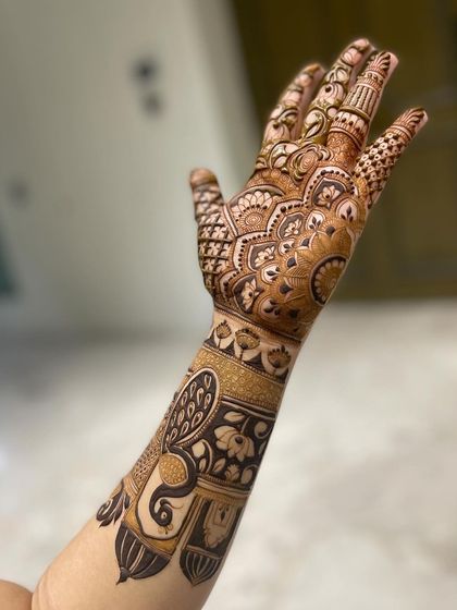 A side profile of a stunning bridal arm mehandi, showing the peacock and jharokha design. The details are sharp and clear.