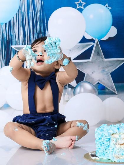 This action shot captures the sheer delight of smashing a cake. With frosting-covered hands held high, it's a memory of pure, uninhibited fun.