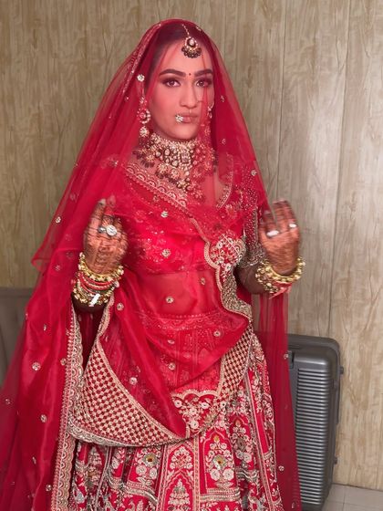 A playful moment with the veil. The sheer red fabric creates a beautiful filter, highlighting the flawless makeup and intricate jewelry underneath.