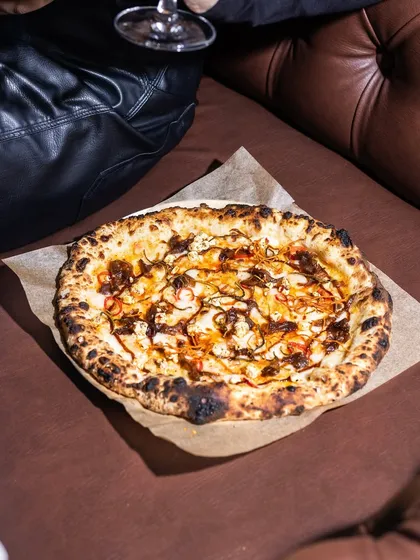 A cozy corner, a glass of wine, and our Caramelised Onion & Feta pizza. The sweetness of the onions and the saltiness of the feta make for an irresistible combination.