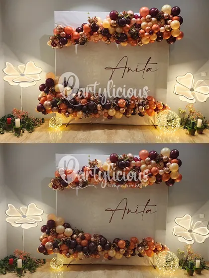 A beautifully understated and elegant backdrop for a birthday celebration. The warm, autumnal tones of the balloon garlands, combined with soft lighting and floral floor lamps, create a cozy and sophisticated ambiance.