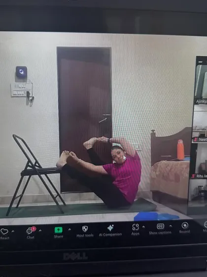 Another student in our online class using a chair to support her in a deep hip-opening pose. This shows how we adapt the practice with props you have at home.