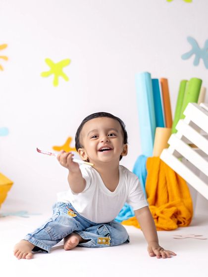 This little artist is having so much fun with his colorful setup. His joyful expression is everything.