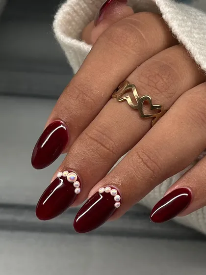A classic deep red manicure gets a sophisticated upgrade with a beautiful pearl accent along the cuticle.