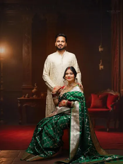 A classic, formal portrait of the couple in traditional attire. This shot showcases the full elegance of the green saree against a rich, dark studio background.
