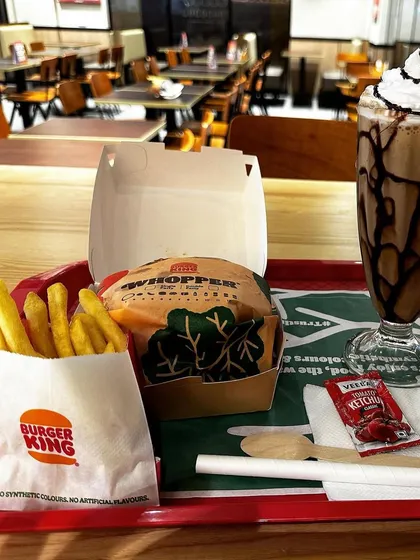 A complete meal tray from Burger King, featuring a Whopper, fries, and a chocolate shake. It's a classic, satisfying meal for any traveler.