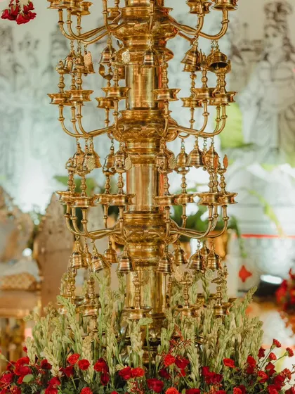 A close-up of one of the custom-made brass pillars, weighing 400kg each. The design features intricate tiers of peacocks, bells, and lamps, showcasing exceptional craftsmanship and attention to traditional detail.