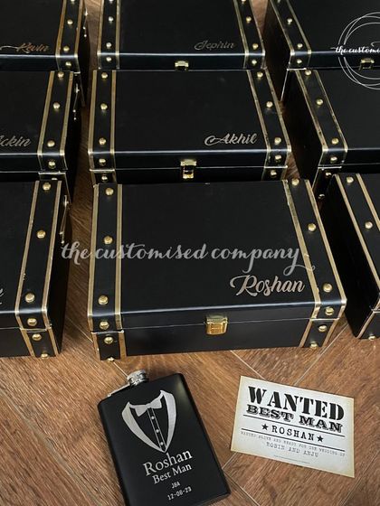 Elevate your groomsmen gifts with these personalized faux leather boxes. Each box is customized with a name and can be filled with items like a custom hip flask and a "Wanted: Best Man" card.