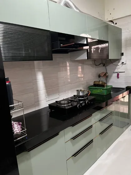 This parallel kitchen in sage green features handleless drawers for a minimalist look. The black countertop and integrated chimney create a seamless and modern design.