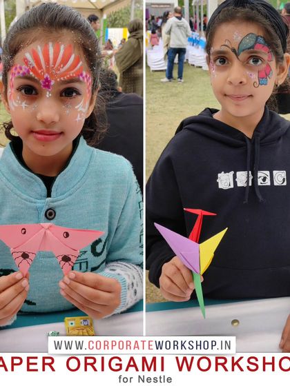 Two girls showing their finished origami butterflies and cranes, with festive face paint from another of our event activities. Our workshops add a memorable, hands-on element to any celebration.