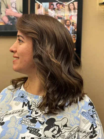 A side view of a client's new cut and color. The soft waves and subtle highlights create a chic and sophisticated style.