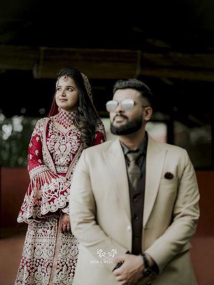 A modern, stylish portrait with the groom in the foreground and the bride standing elegantly behind him.