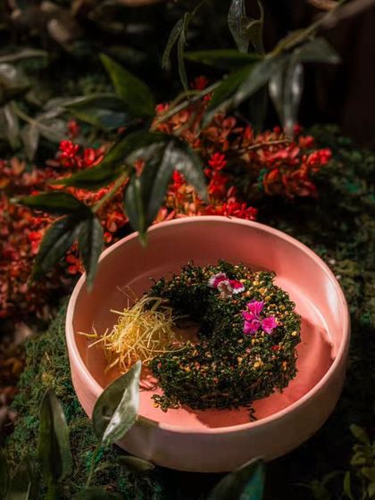 Even the food presentation is enhanced by the garden. This image shows a gorgeously plated dish from the restaurant, nestled within the moss and leaves of our installation, creating a unique and memorable visual for diners.