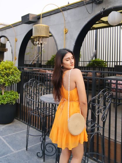 A full shot of the yellow dress on a beautiful rooftop. The backless detail and flowy fabric are perfect for summer.