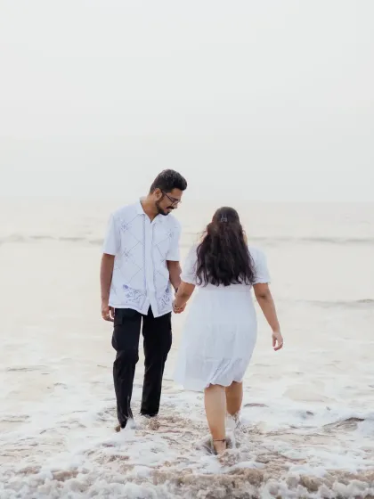 A candid shot of the couple walking into the waves, capturing a sense of adventure and shared journey.