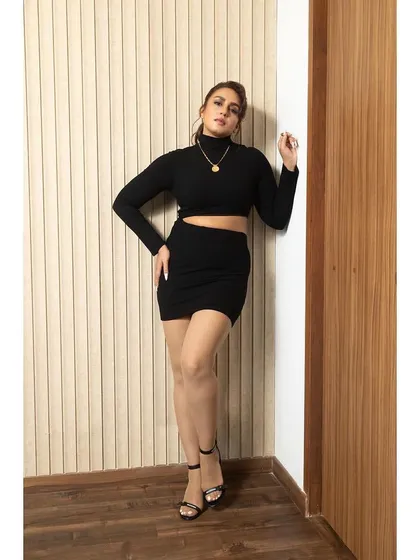 A full-length view of the black Superdown set, showing the mini skirt and turtleneck crop top.