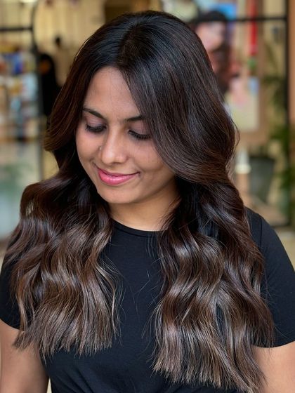 The client is smiling, clearly happy with her subtle yet impactful hair transformation. The color looks natural and healthy.