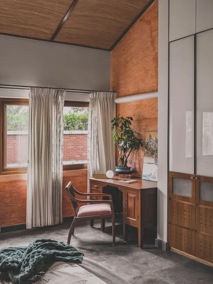 This bedroom study corner combines rustic and refined elements. The textured terracotta wall adds warmth and character, while the clean lines of the wardrobe and desk maintain a sense of modern simplicity.
