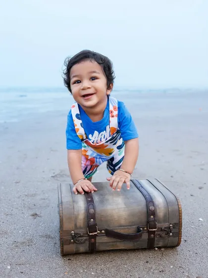 A little adventurer on the beach, ready to explore with his vintage suitcase prop during his first birthday session.
