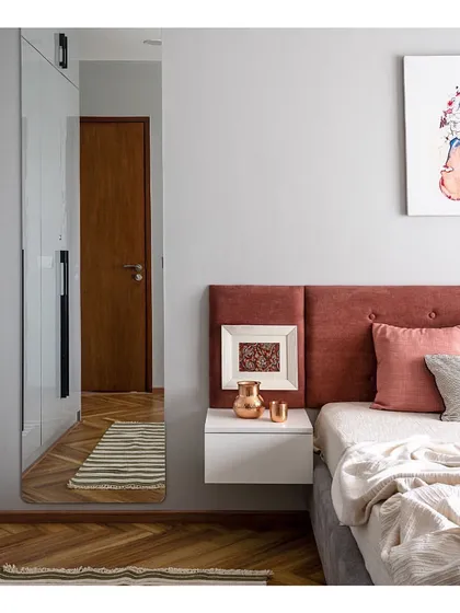 The guest bedroom is a welcoming space with a pop of personality. A rust-colored headboard and vibrant modern art piece contrast with the cool grey tones of the wardrobe and walls, creating a balanced and stylish room.