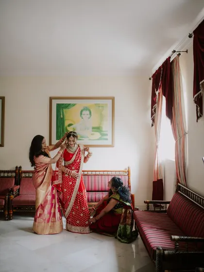A candid moment of the bride getting ready, with her mother and another family member helping with her final touches. These family interactions are a precious part of the wedding story.