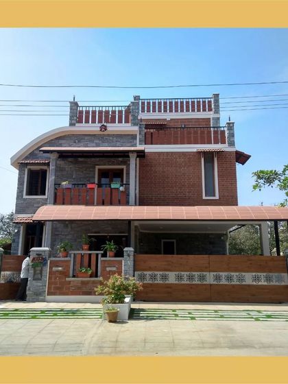 The facade of the Hemavathi and Hareesh residence, featuring a unique curved roofline and a blend of grey stone and red brick for a distinctive look.