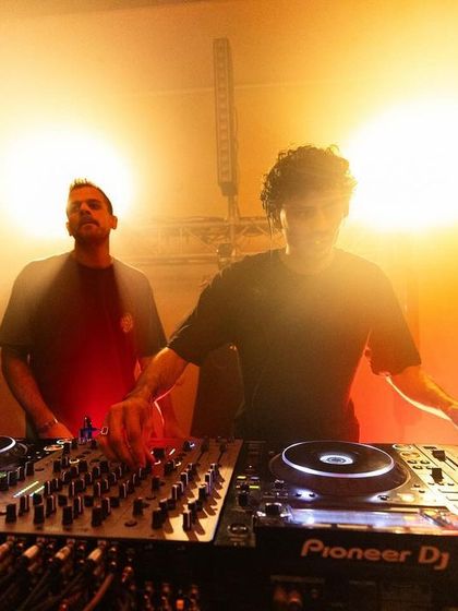 A DJ commands the stage, backlit by a warm, powerful glow. Our events are designed to be a complete sensory experience, with top-class audio-visual rigging to match the talent.