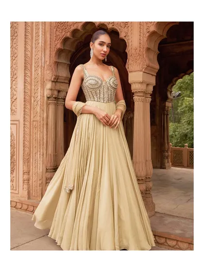 Made to move and styled to stand out, this flowing gown in a soft beige is ideal for sangeets and cocktails. The embellished bustier and pleated skirt create a silhouette that is both graceful and glamorous.