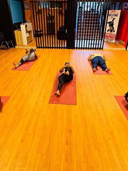 A group of members holding a deep knee-to-chest stretch. This is great for releasing the lower back and improving hip mobility.