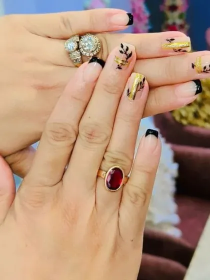 A creative French manicure combining black tips with accent nails featuring gold foil and delicate black leaf patterns. This design is artistic and perfect for a unique, stylish look.