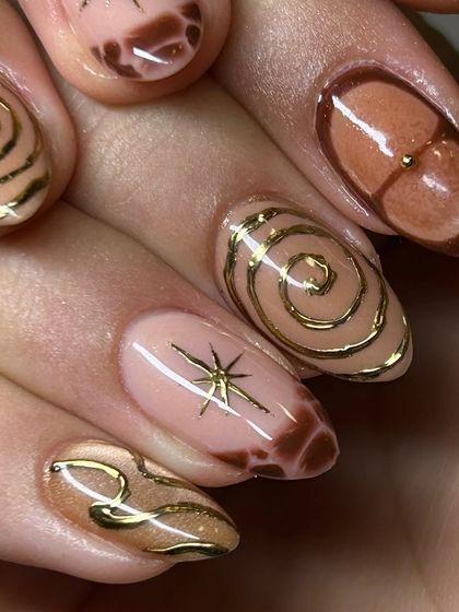 A close-up of the intricate details in this abstract brown and gold nail art set, highlighting the hand-painted swirls and starburst.