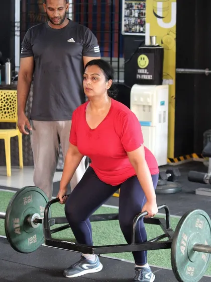 Form is everything. Here, I am guiding a client through a trap bar deadlift, ensuring her posture is correct to maximize strength gains and prevent injury. This is what personalized coaching looks like.