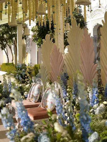 A close-up of the mandap decor, showing the intricate silver chairs and the pastel feather panels.