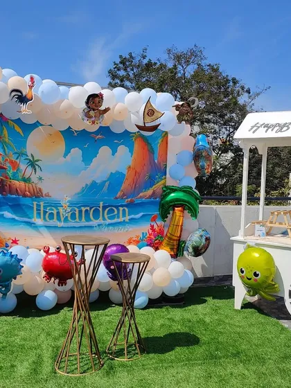 Taking the party outdoors with a vibrant Moana theme. I used a custom printed backdrop of a beach scene, framed by a blue and white balloon garland with character foil balloons. The setup is completed with a cute party cart, perfect for serving treats on a sunny day.