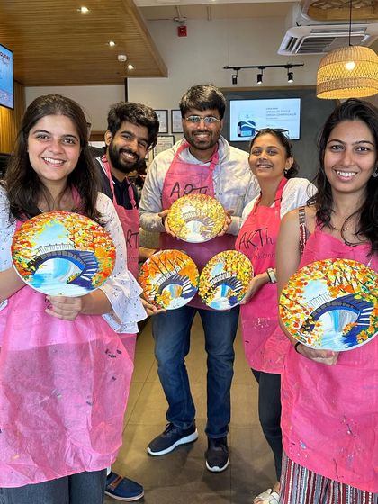 A group of five friends with their finished plate paintings. Painting on unconventional surfaces like plates is a fun twist.
