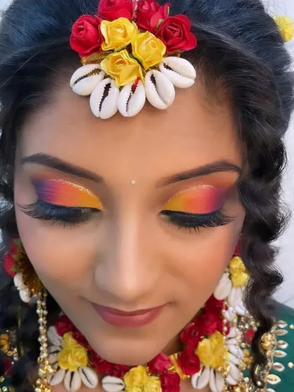 Another beautiful Haldi look, this time featuring a sunset-inspired eye with a blend of orange and yellow. The floral jewelry made with shells adds a unique, modern twist.