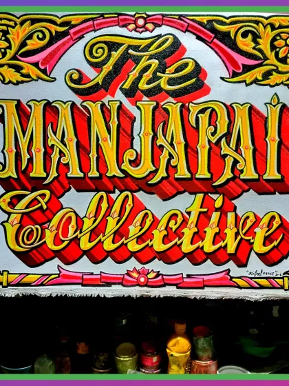 A finished sign for "The Manjapai Collective" in Bengaluru. The piece features intricate border work in pink and yellow, framing the bold, 3D red and yellow lettering.