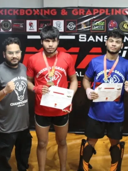 Two fighters with their medals, flanked by their coaches, after the MFC Series 2.