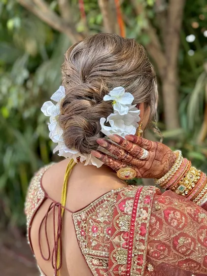 The hairstyle is a crucial part of the bridal look. This textured bun with fresh white flowers is a classic choice that adds a touch of romance.