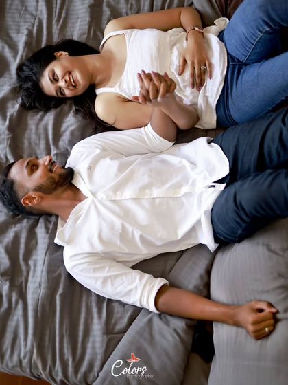 A relaxed overhead shot of the couple lying down, holding hands and sharing a smile.